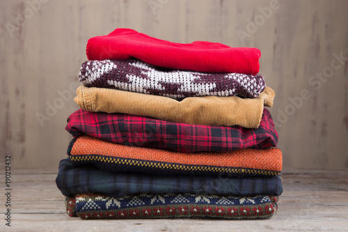 Pile of knitted winter sweaters on wooden background