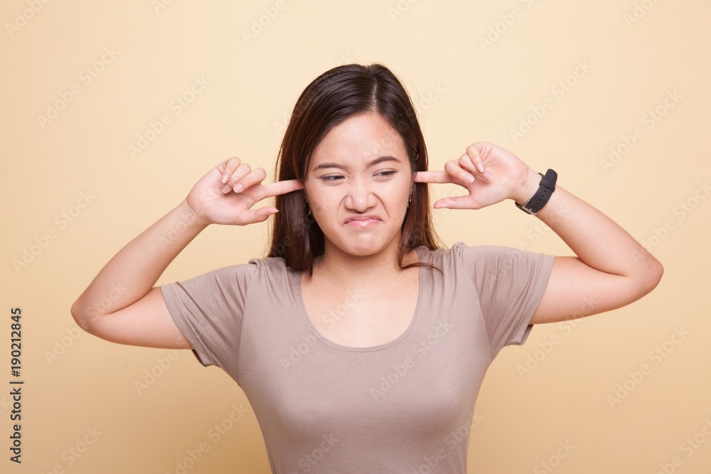 Fototapeta premium Young Asian woman block both ears with fingers.
