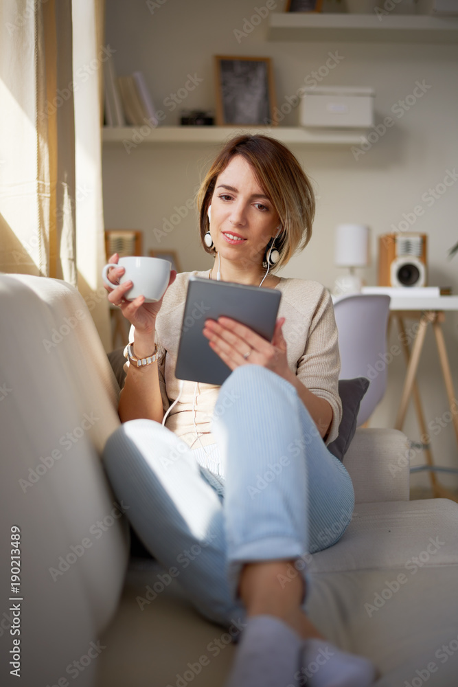 Woman sitting on sofa and using tablet. Woman sitting on sofa and using tablet.