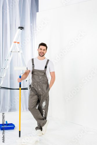 smiling handsome man standing with paint roller brush