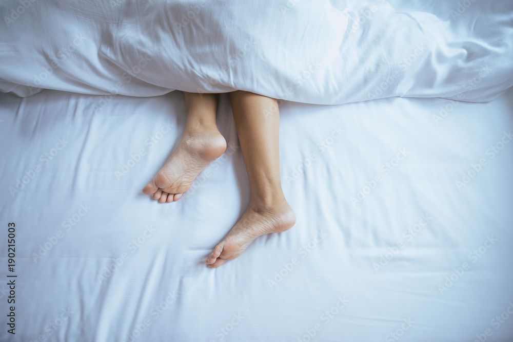 Barefoot and leg under blanket on the bed,Top view Barefoot and leg under blanket on the bed,Top view