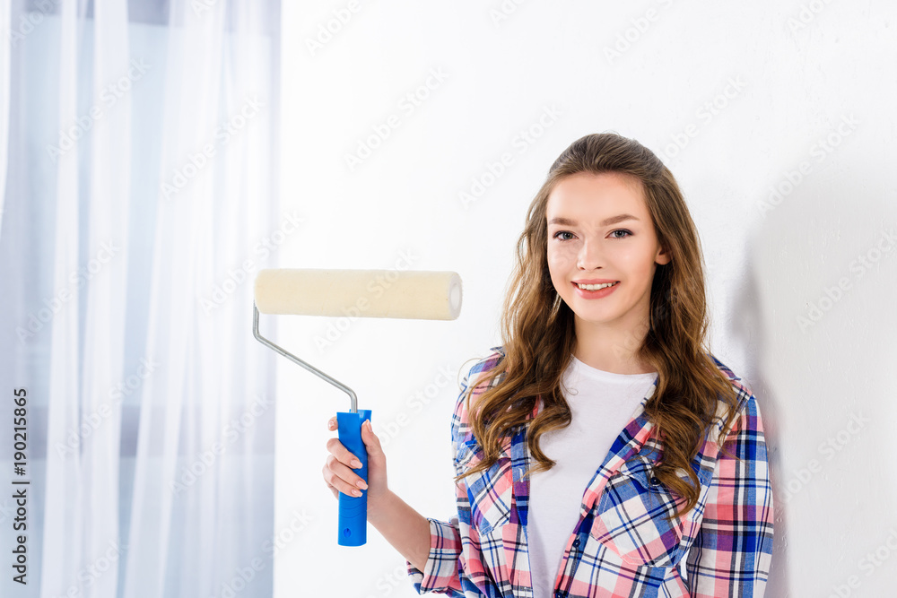 smiling girl holding paint roll brush and looking at camera smiling girl holding paint roll brush and looking at camera