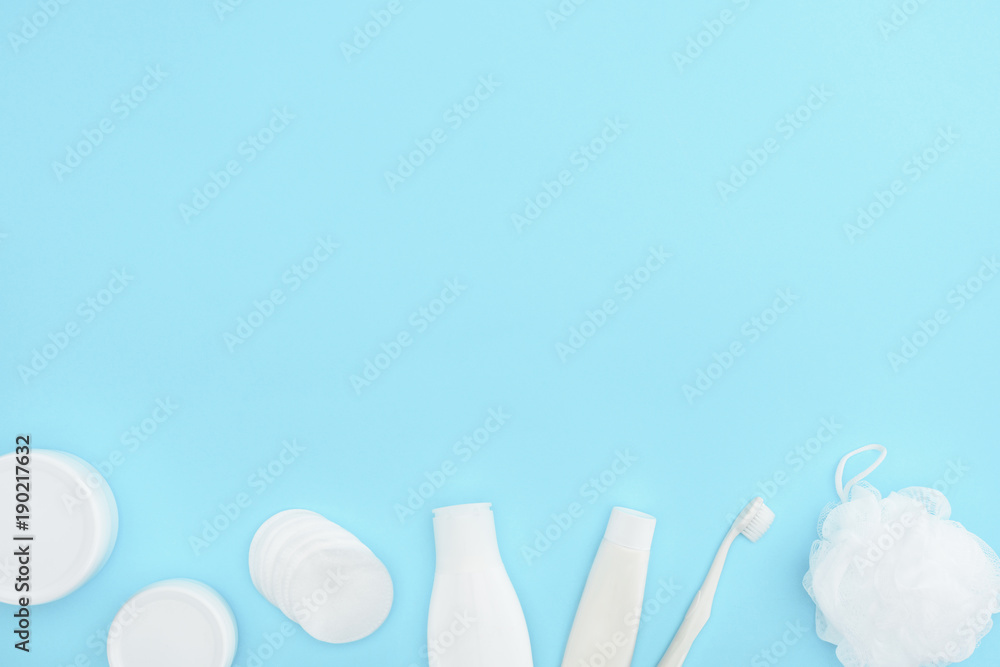 top view of plastic containers and bottles with cream, sponge, toothpaste and toothbrush, isolated on blue top view of plastic containers and bottles with cream, sponge, toothpaste and toothbrush, isolated on blue