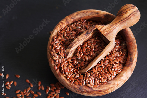 Organic flax seed in wooden bowl on black slate background copy space. Linum usitatissimum © Maria Medvedeva