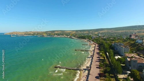 Aerial view: Sea, beach, sea, resort town of Feodosiya, Crimea vacation on Black sea. Dreamland beach from aero view tourists relaxing and swim, city aerial pan tilt up Cremea black sea beach Feodosia photo