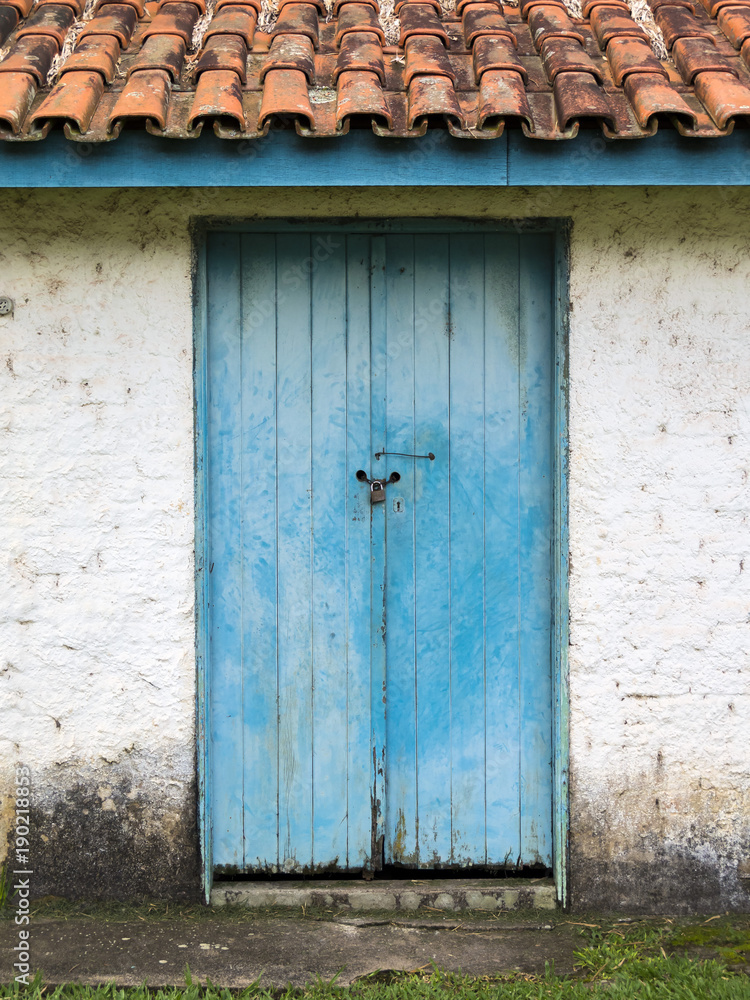 blue door with a padlock in a white brick farm house in brazil