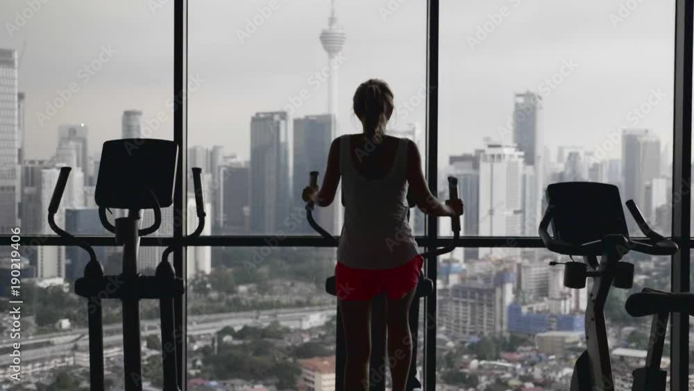 Young woman working out hard in sports club.Attractive girl at the gym riding on the spinning bike with great view over city.Active, healthy lifestyle and loosing weight concept. Young woman working out hard in sports club.Attractive girl at the gym riding on the spinning bike with great view over city.Active, healthy lifestyle and loosing weight concept.