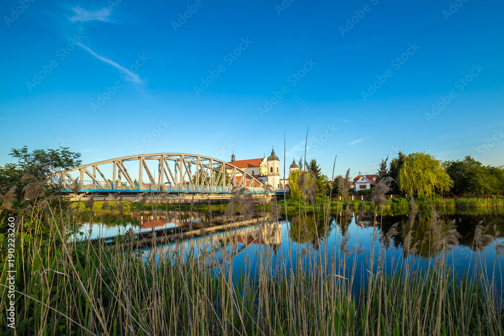 View at bridge over the Narew river and baroque Church of the Holy Trinity in Tykocin town, Podlasie, Poland