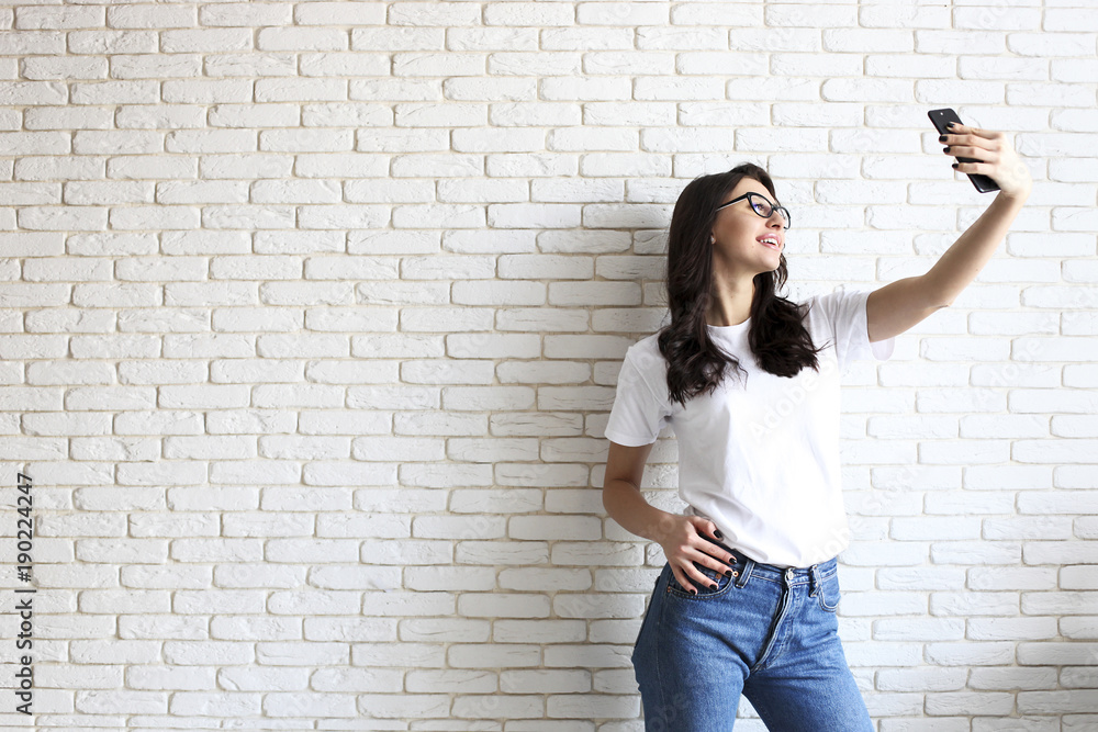 Stylish woman making selfie with shopping bag on the yellow wall background. Winter holiday sale Stylish woman making selfie with shopping bag on the yellow wall background. Winter holiday sale
