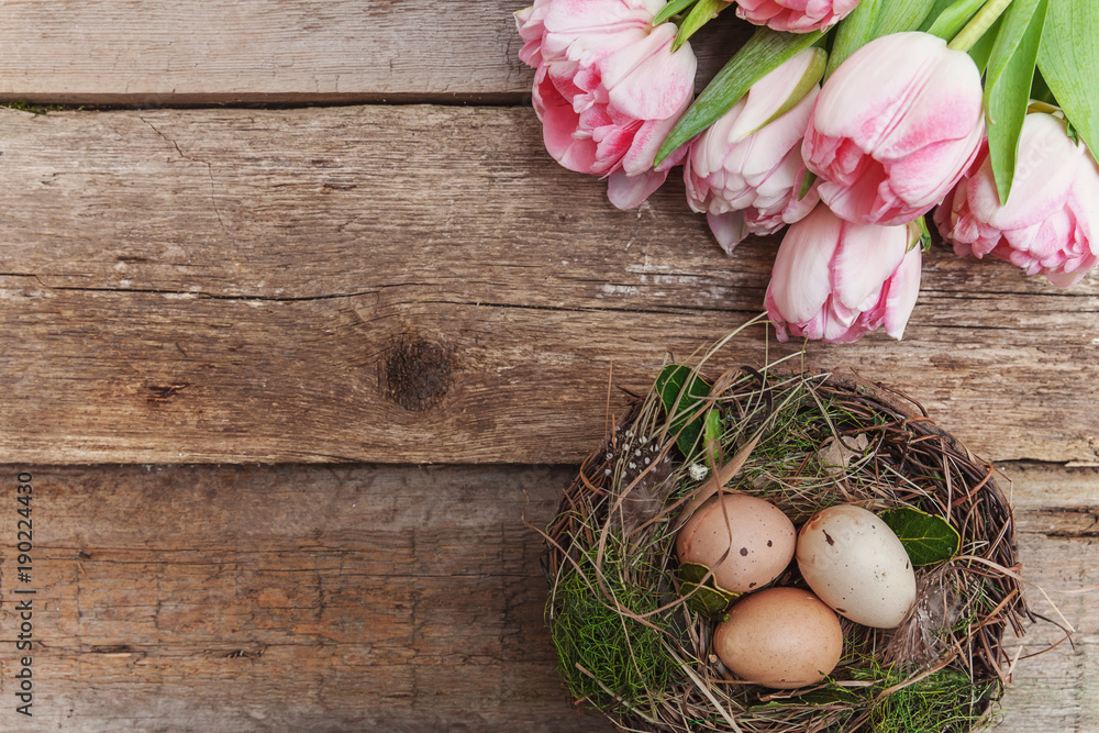 Happy easter greeting card. Easter eggs in nest with pink tulips on rustic wooden background flat lay. space for text, top view Happy easter greeting card. Easter eggs in nest with pink tulips on rustic wooden background flat lay. space for text, top view