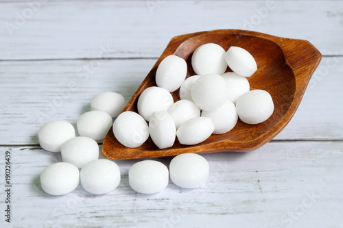 White naphthalene balls on white wooden background