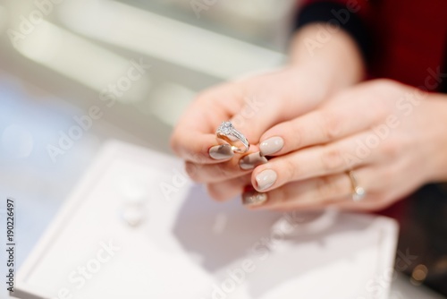 Female seller in a luxury jewelry store presents a ring.