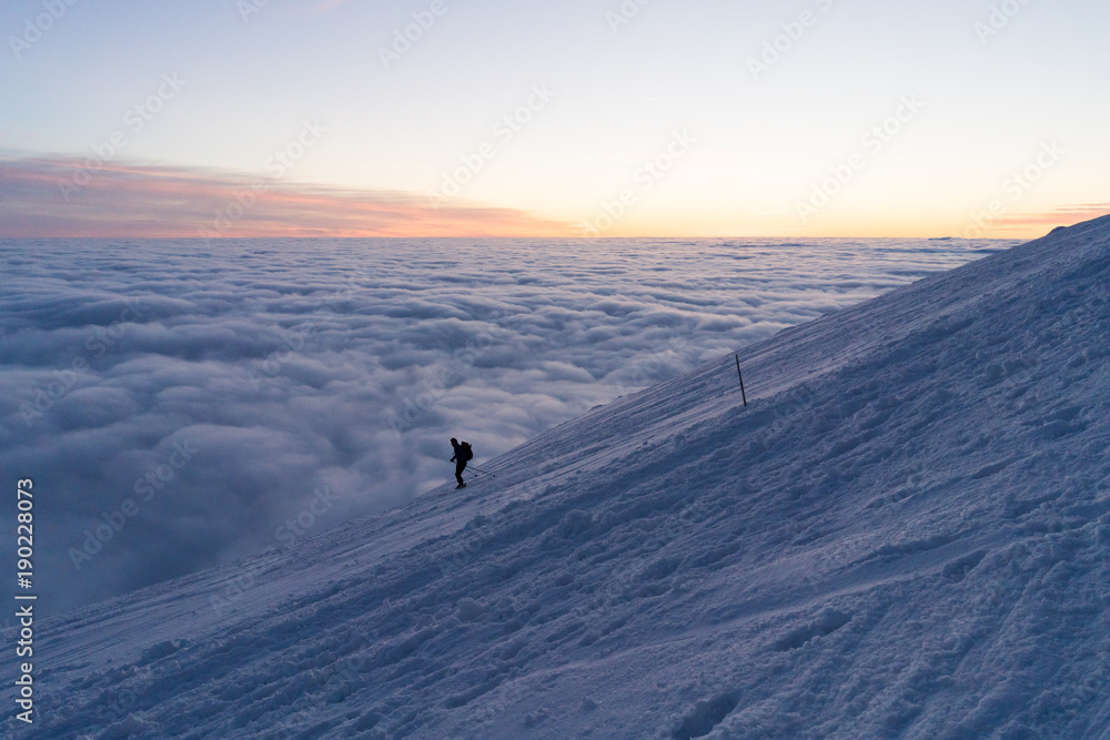 Skiing on snow in Slovak mountains above clouds during sunset in winter