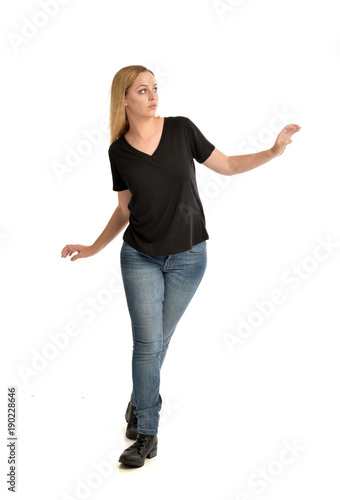 full length portrait of blonde girl wearing black shirt and jeans, standing pose isolated on a white background.