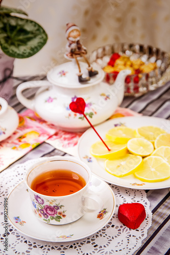 Porcelain cup of tea with lemon and sweets