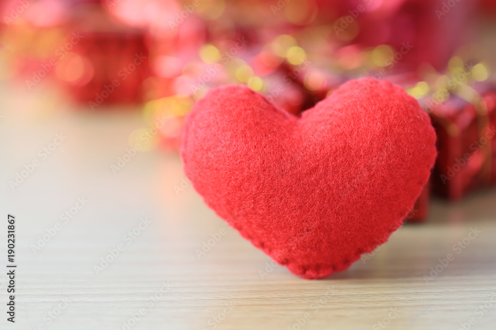 red heart placed on a wooden floor on red gift box of blur background. red heart placed on a wooden floor on red gift box of blur background.