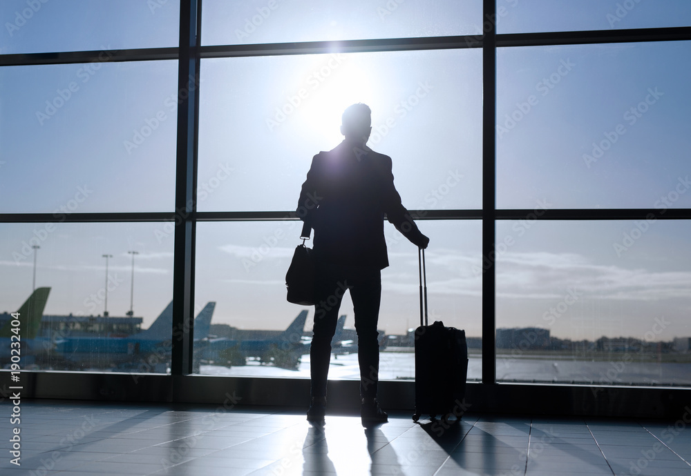 Businessman standing with suitcase in airport Businessman standing with suitcase in airport
