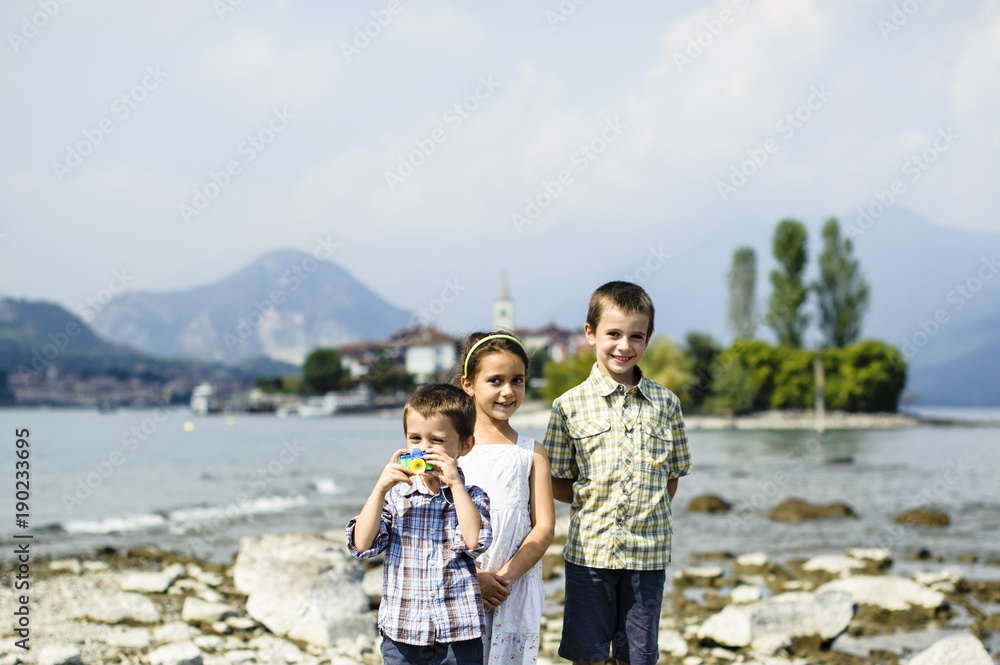 portrait of three children brothers and sister in outdoor on the shores of Lake Maggiore Italy tourists in the summer