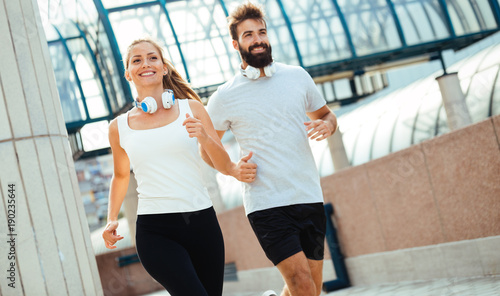 Young fitness couple running in urban area