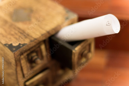 Rolling white paper that represent love message in the drawer of a little box in wood