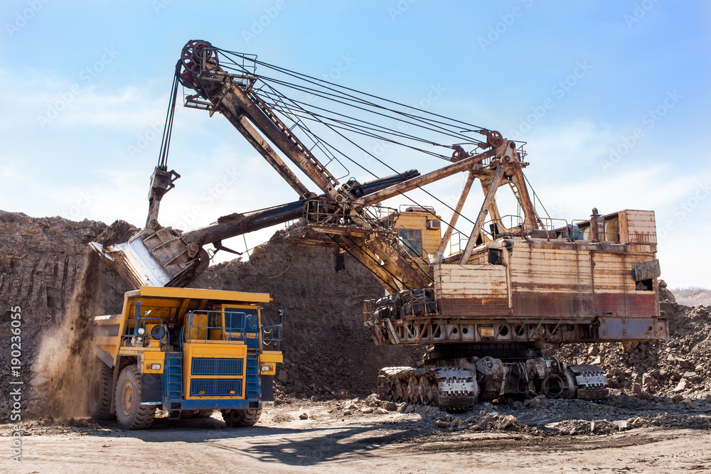 Excavator loading yellow dump truck