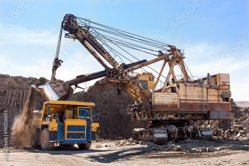 Excavator loading yellow dump truck