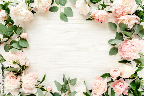 Fototapeta Naklejka Na Ścianę i Meble -  Floral pattern, frame made of pink peonies  branches of eucalyptus and leaves on wooden white background. Flat lay, top view. Valentine's background. Floral frame. Frame of flowers. Flowers texture