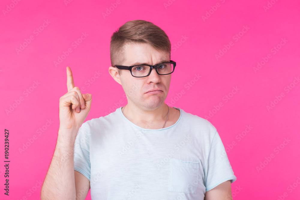 Young man raises fore finger as recieves good idea. Excited man remind something, isolated on pink Young man raises fore finger as recieves good idea. Excited man remind something, isolated on pink