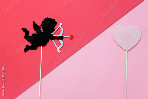 Flat lay aerial image of sign of valentines 's day background concept.DIY photo booth props the cupid shoot arrow to red heart on modern rustic pink wallpaper at home office desk studio.pastel tone.