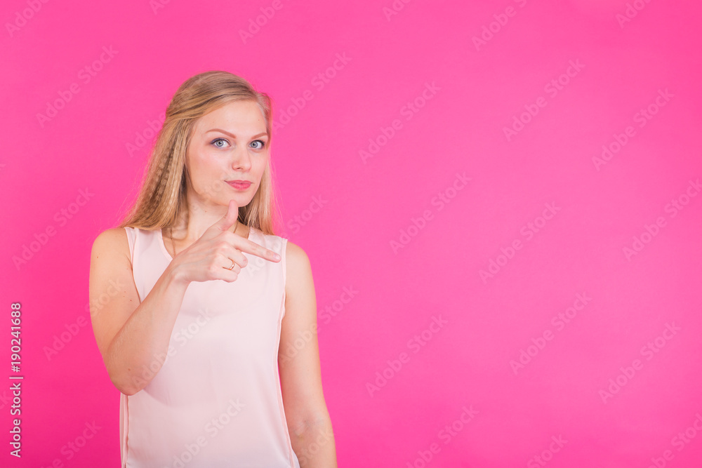 Young woman pointing at pink background with copy space Young woman pointing at pink background with copy space
