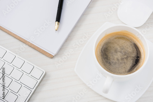 close up view of arranged computer keyboard, mouse, cup of coffee and papers on table