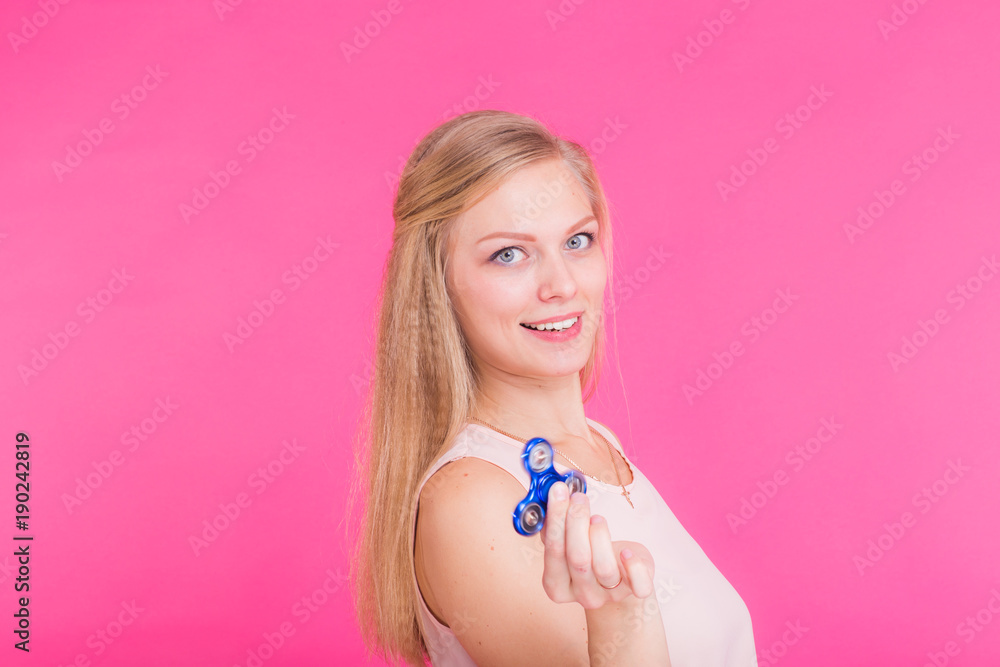 Young woman on a pink background holds a spinner. Young woman on a pink background holds a spinner.