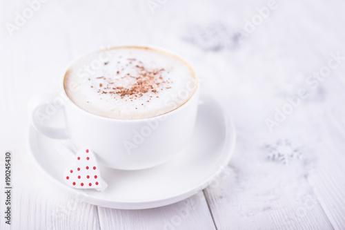 Happy Valentine's day! White cup with cappuccino and red heart on a white wooden background. Free space