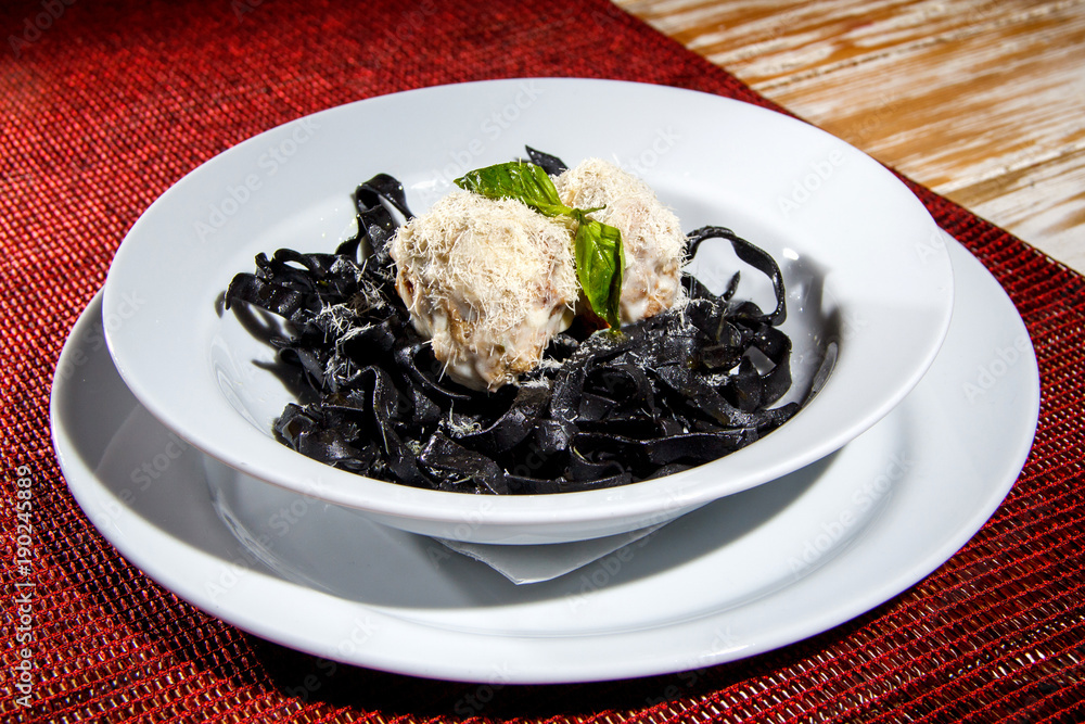 Black Cuttlefish ink Pasta with nuts balls and fresh mint. Closeup.