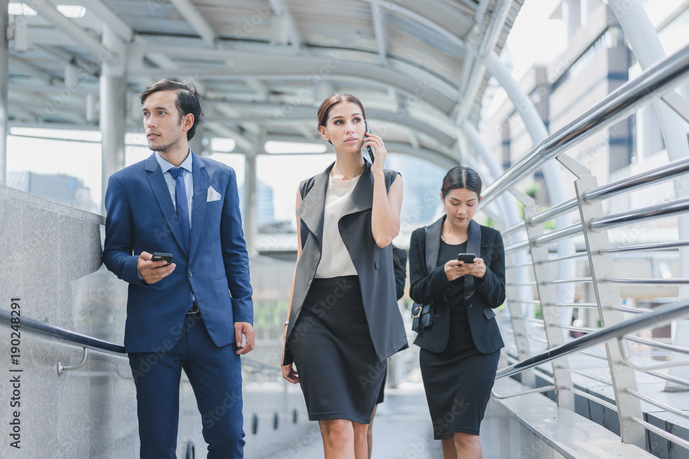 Professional business team using smartphone talk business project while walking forward confidently in cityscape background Professional business team using smartphone talk business project while walking forward confidently in cityscape background