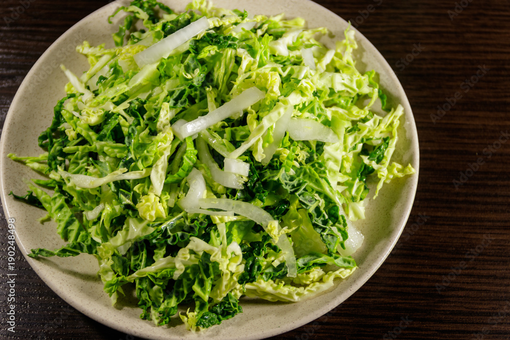 Salad with savoy cabbage and onion on wooden table Salad with savoy cabbage and onion on wooden table
