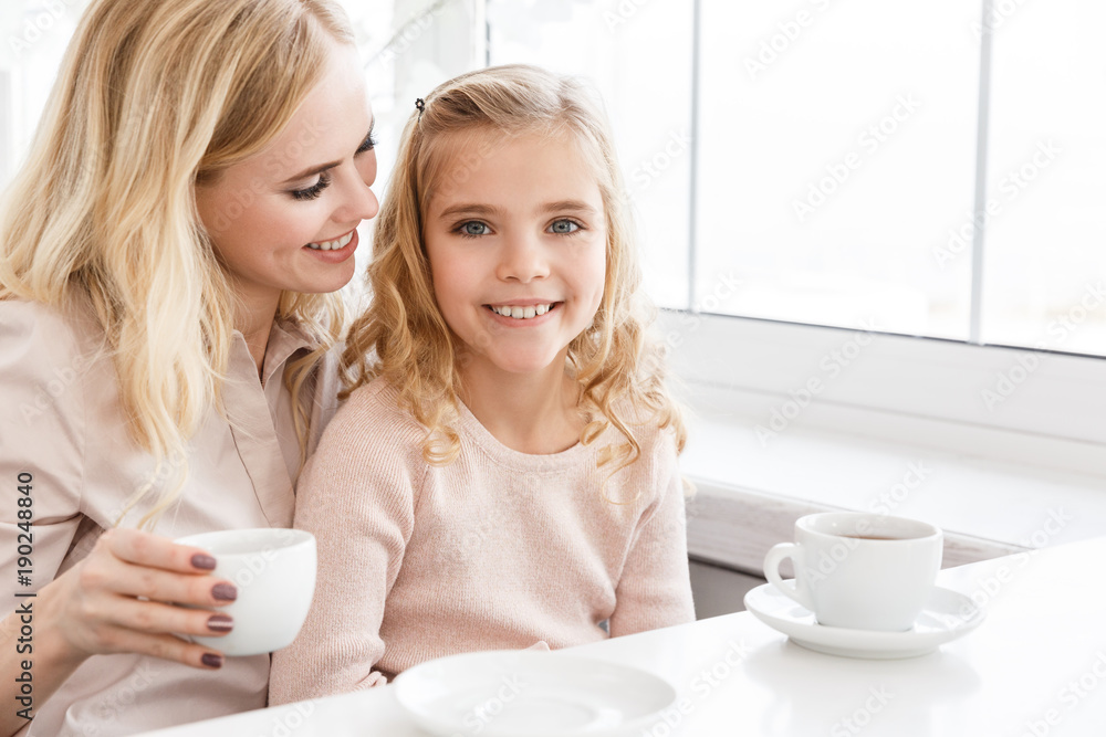 mother and beautiful little daughter drinking tea together