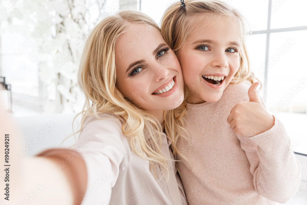 young beautiful mother and daughter taking selfie and showing thumb up young beautiful mother and daughter taking selfie and showing thumb up