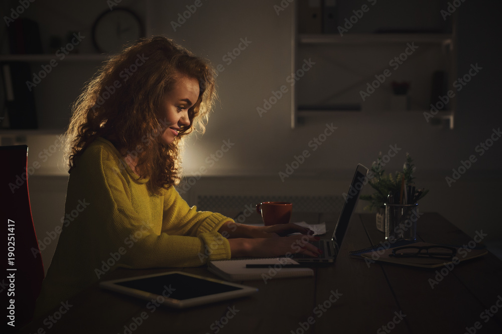 Freelancer working on laptop at home until late evening Freelancer working on laptop at home until late evening