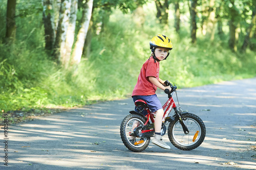 Portrait of a cute boy on bicycle, wearing safety helmet © Petr Bonek