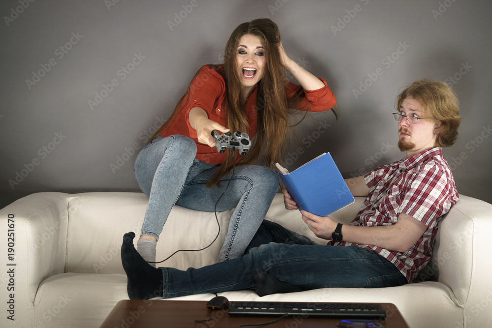 Woman playing games man reading book Woman playing games man reading book
