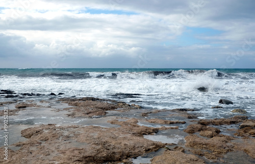 Storm waves break about the coastal stones against the cloudy sky on overcast day