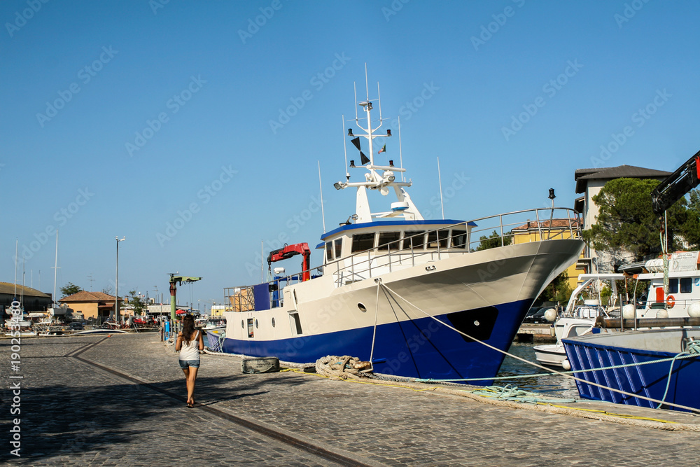 Summer. Italy. Cesenatico. Museum of the ships. The boat is white and blue. Embankment.