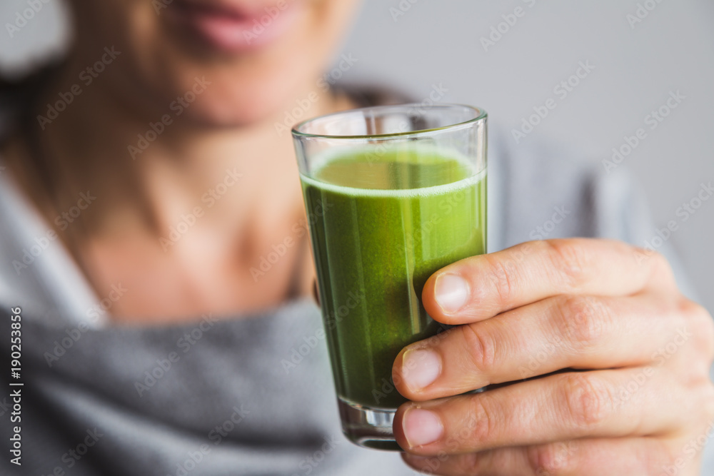 Healthy woman drinking shot of wheatgrass juice Healthy woman drinking shot of wheatgrass juice