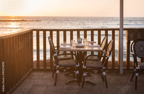 Served table in the restaurant on the sea sunset background © Olesya