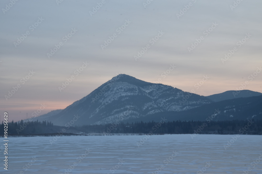 Pink Sunrise over a snowy mountain peak with frozen lake in the foreground Pink Sunrise over a snowy mountain peak with frozen lake in the foreground