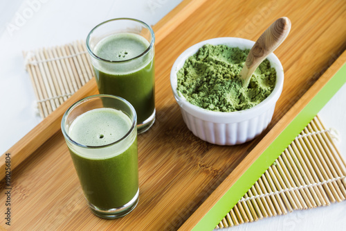 Wheatgrass shots with powdered wheatgrass and wooden spoon photo