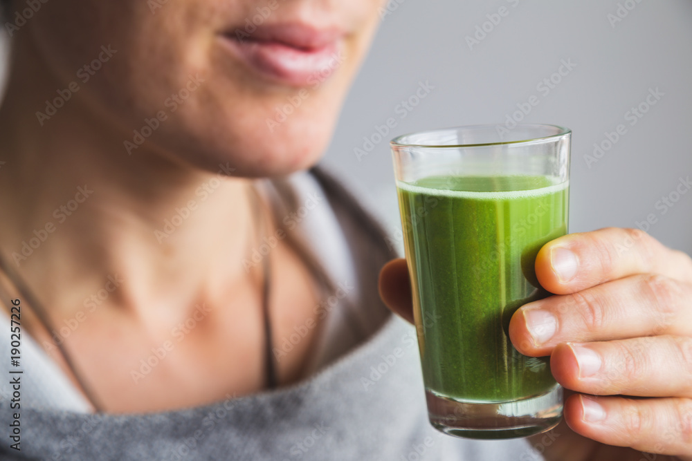 Woman holding shot of wheatgrass juice