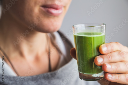 Woman holding shot of wheatgrass juice photo