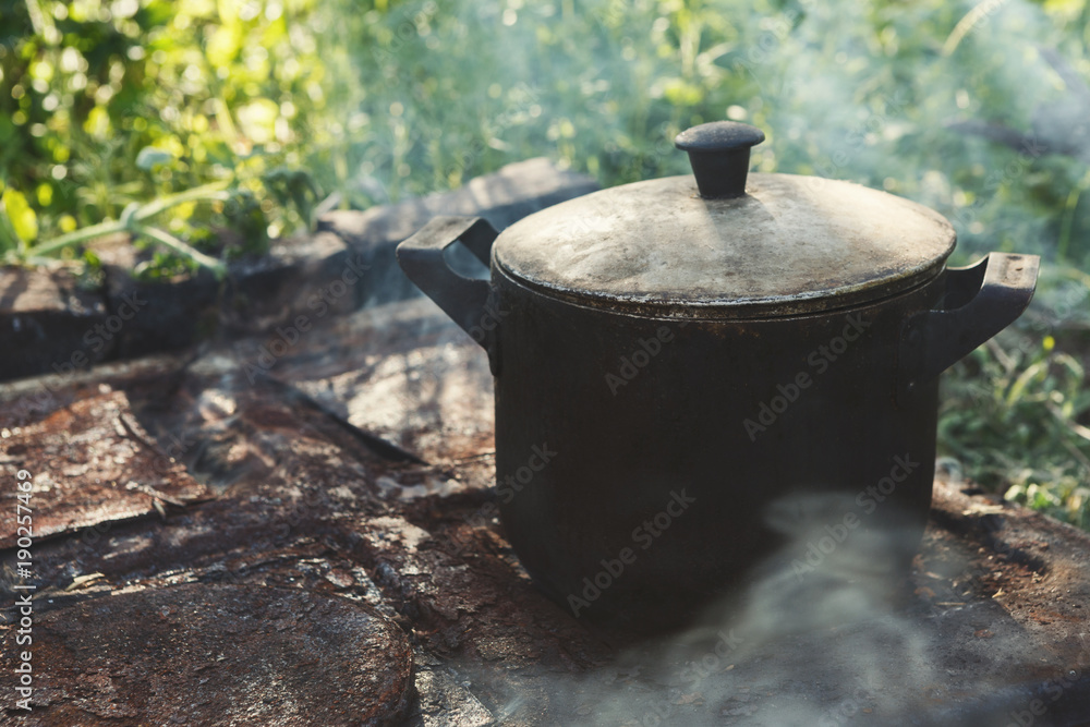 Cooking dinner in old camping kettle on picnic. Closeup. Cooking dinner in old camping kettle on picnic. Closeup.